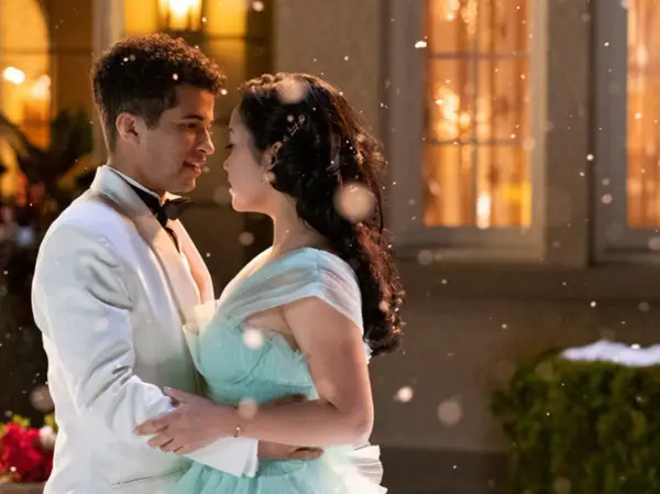 Jordan Fisher dans une scène romantique de films et séries tv. Il danse avec une jeune femme en robe bleu pâle, sous une pluie de flocons.